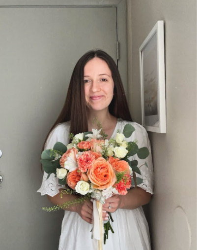 Bryli holding a coral, cream, and eucalyptus bouquet