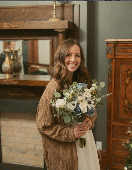 Bryli holding a white, blue, and eucalyptus winter bouquet